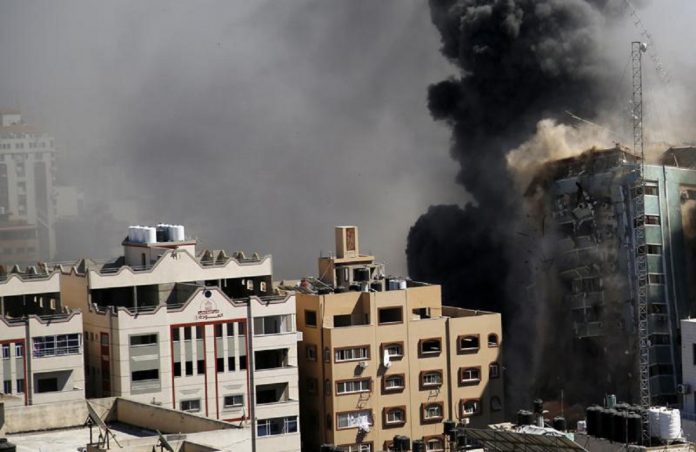 Une vue d'un immeuble de 11 étages abritant le bureau de l'AP et d'autres médias dans la ville de Gaza est vue quelques instants après la démolition des avions de combat israéliens, samedi 15 mai 2021.