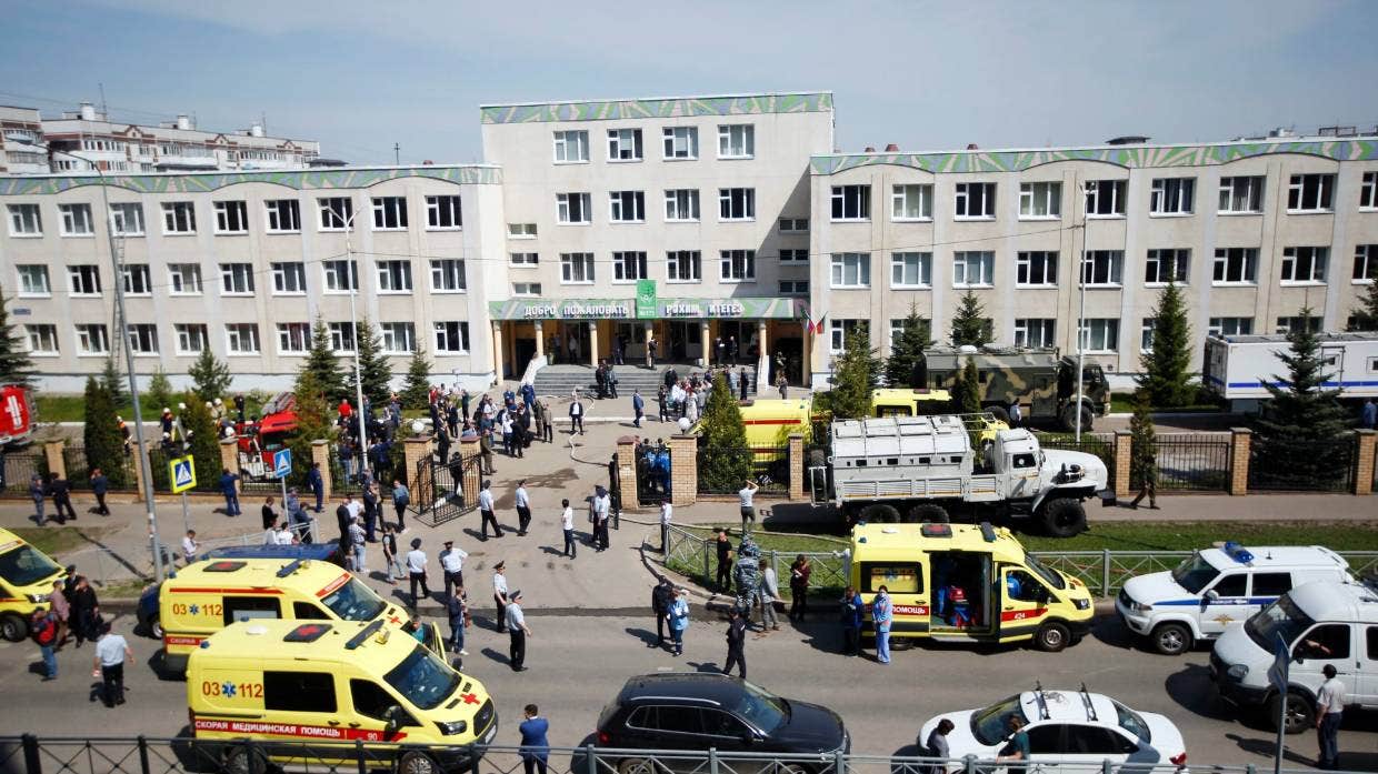 Des ambulances et des voitures de police et un camion sont garés dans une école après une fusillade à Kazan, en Russie, le mardi 11 mai 2021