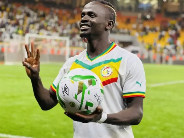 Sadio Mané tenant un ballon en main et souriant
