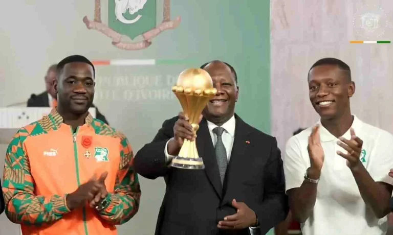 Alassane Ouattara tenant la coupe en main , accompagné de Emerse Faé et de Max-Alain Gradel